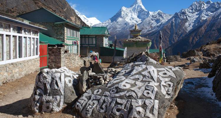 Pierres de prière et bâtiments avec de hautes montagnes en arrière-plan.