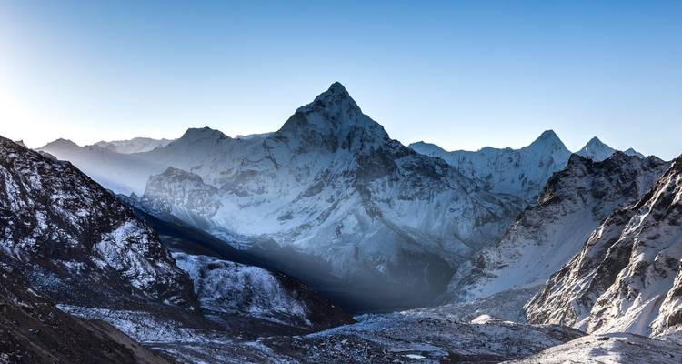 Hauts sommets montagneux enneigés projetant des ombres dramatiques.