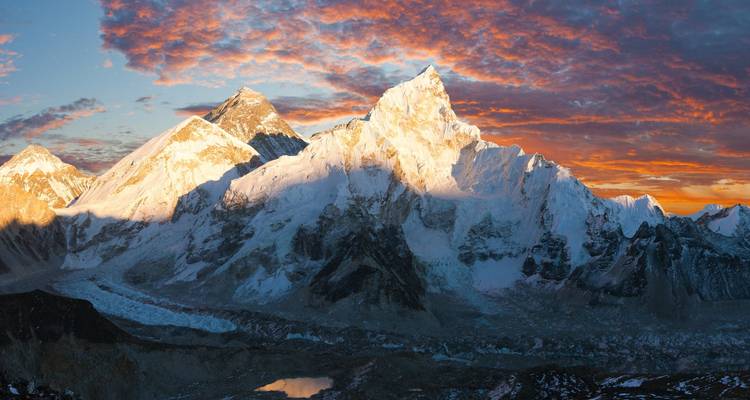 Pics dramatiques de l'Himalaya sous un coucher de soleil vibrant.