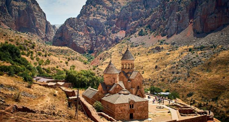 Monastery complex set amidst rocky mountains under a clear sky.