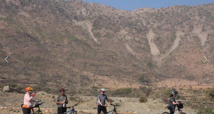 Cyclists with helmets in front of a mountainous backdrop.