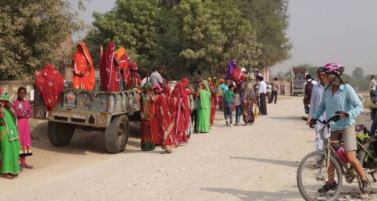 Colorful traditional dresses worn by people gathered on a dirt road.