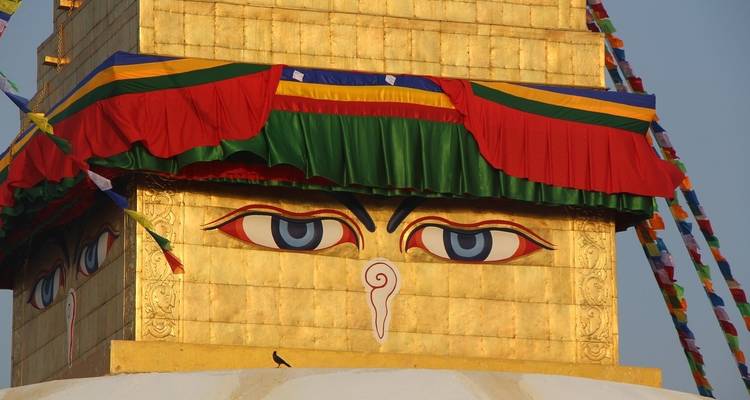 Golden stupa with iconic eyes and prayer flags around.