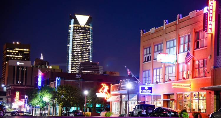 Cityscape at night with neon lights and high-rise buildings.