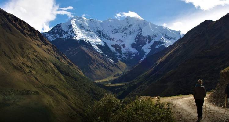 Una persona haciendo trekking en un valle con montañas nevadas en Perú.