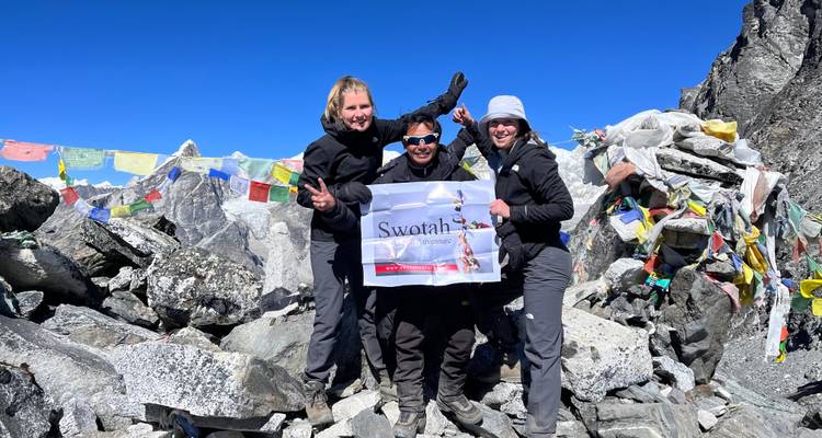 Gruppe von Wanderern, die eine Flagge an einem felsigen Bergpass halten.