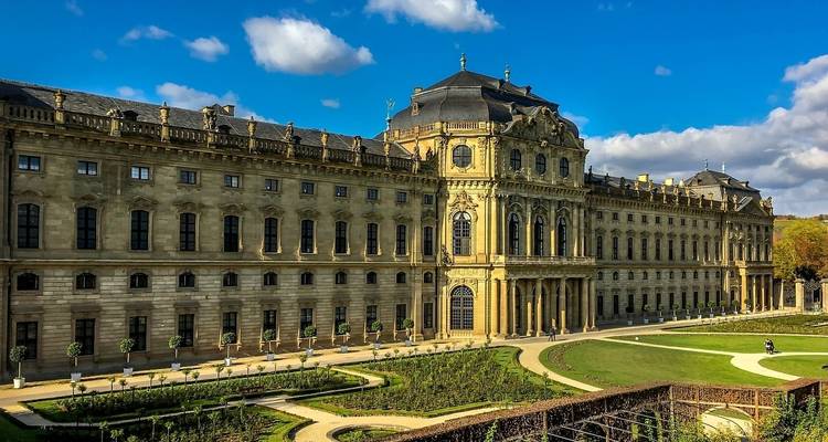 Un grand palais historique avec un jardin et un ciel bleu.