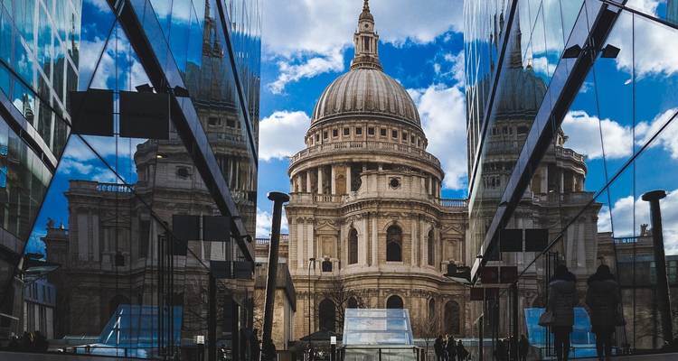 St. Paul's Cathedral spiegelt sich in modernen Glasgebäuden wider, während Fußgänger durch die Passage gehen.