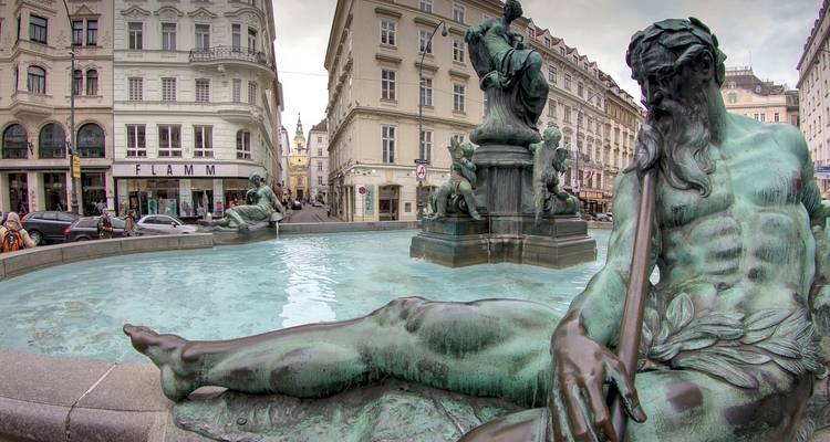 Sculptures décoratives entourant une fontaine dans une ville européenne.