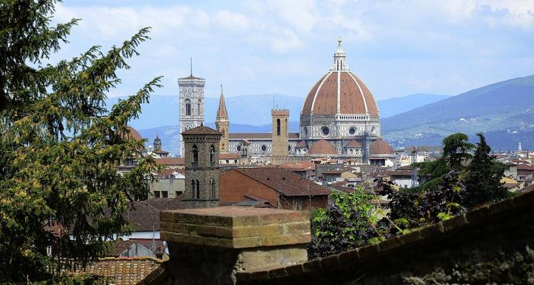 Vista de Florencia con la cúpula de tejas rojas del Duomo elevándose sobre los techos de la ciudad y colinas lejanas.