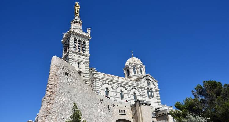 La basílica de Notre-Dame de la Garde encaramada bien arriba de Marsella brilla contra un cielo azul profundo.