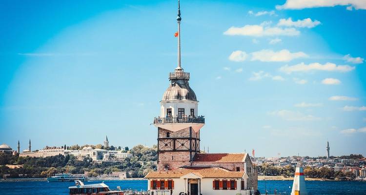 La Torre de la Doncella se alza en las aguas azul brillante frente a Estambul con el horizonte de la ciudad de fondo.