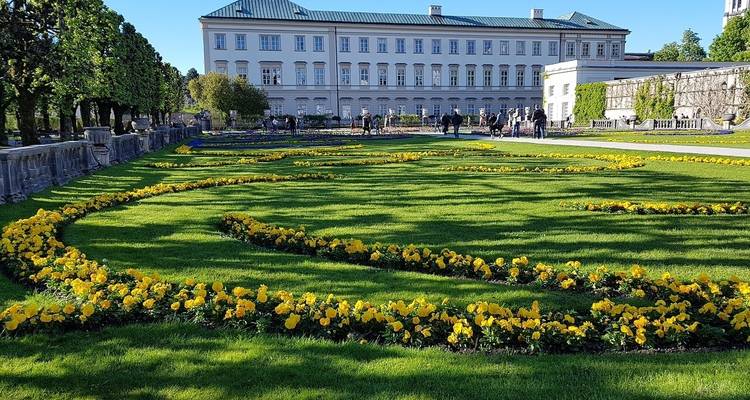 Schöner Garten mit gelben Blumen und einem historischen Gebäude.