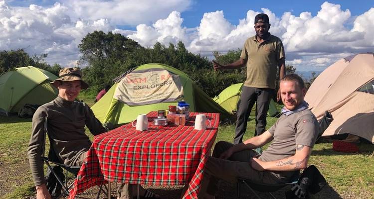Personas sentadas en un campamento con tiendas de campaña