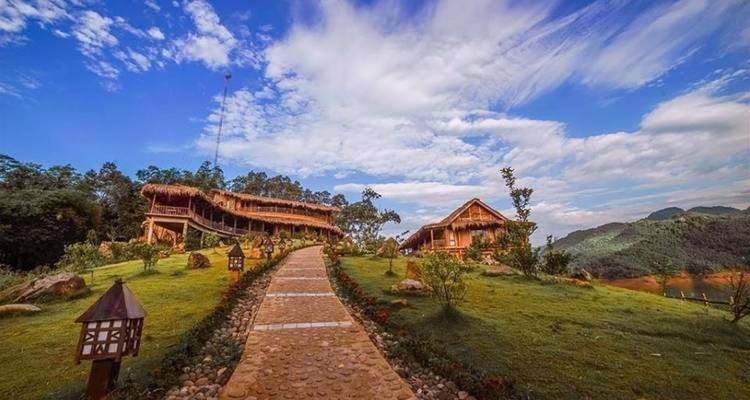 Thatched roof houses and a stone pathway in a hilly landscape.