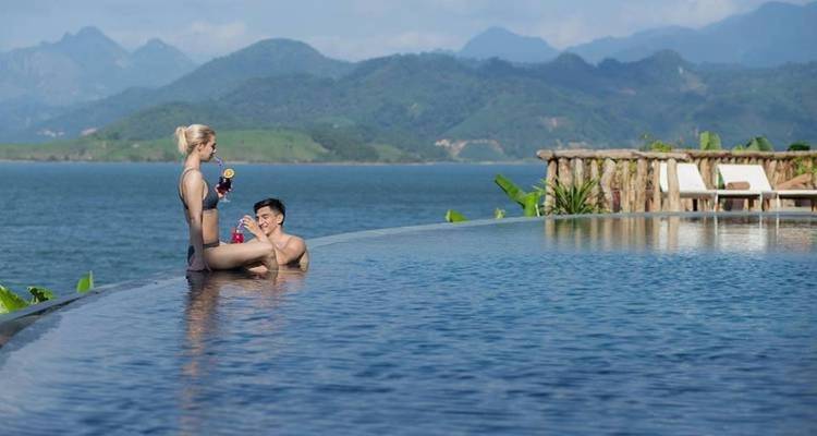 Couple in a pool with a scenic view of a lake and mountains.