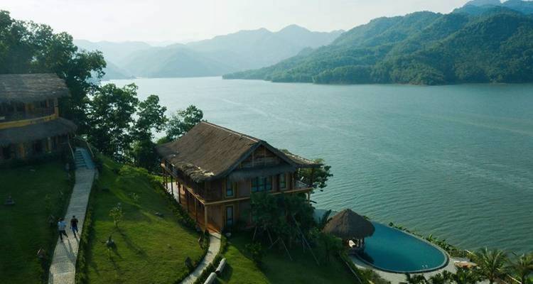 Lakeside resort with traditional buildings and lush greenery.