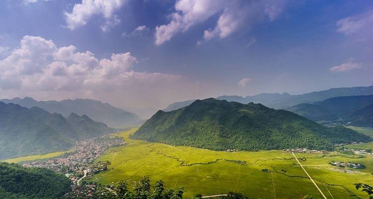 Weites Tal mit Bergen im Hintergrund unter einem dramatischen Himmel