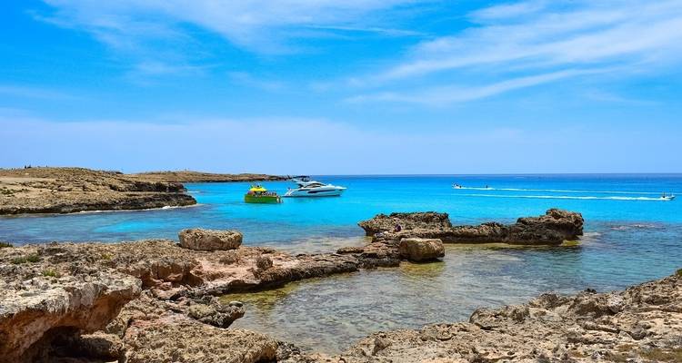 Boten op een turquoise blauwe zee met rotsachtige omgeving.