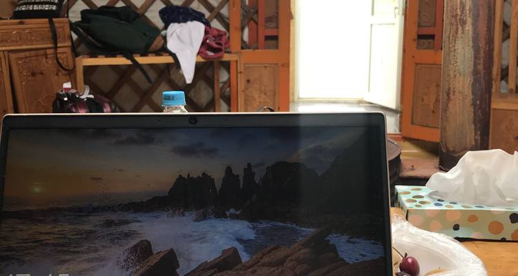 Inneres einer Jurte mit einem Laptop-Bildschirm, der eine felsige Meeresküste zeigt.