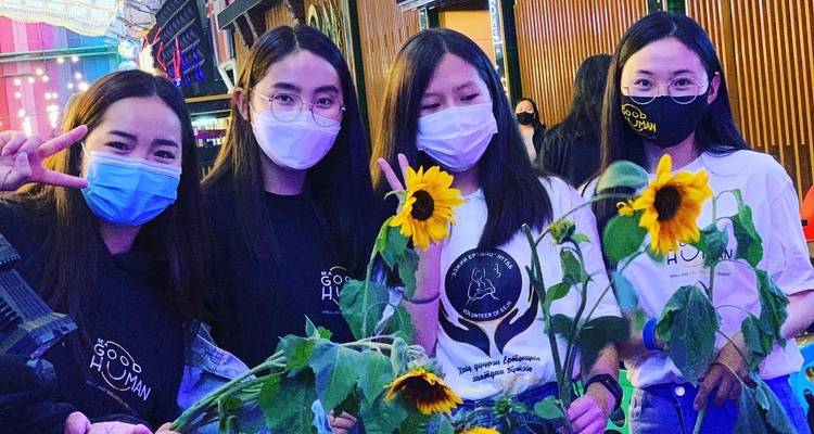 Vier Frauen posieren mit Sonnenblumen drinnen.