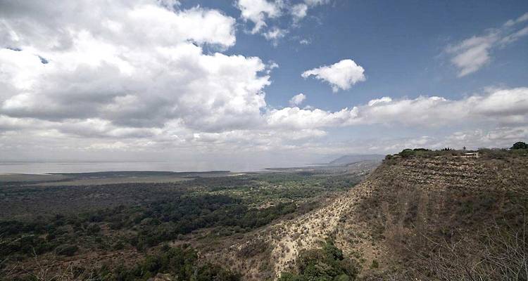 Vista panorámica sobre el escarpe del Valle del Rift con bosques, lago y cielo nublado.