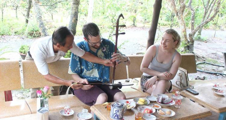 Tres personas disfrutando de una lección de música con refrigerios en una mesa.