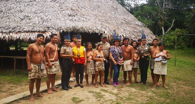 Group of locals and tourists posing in front of a thatched building.
