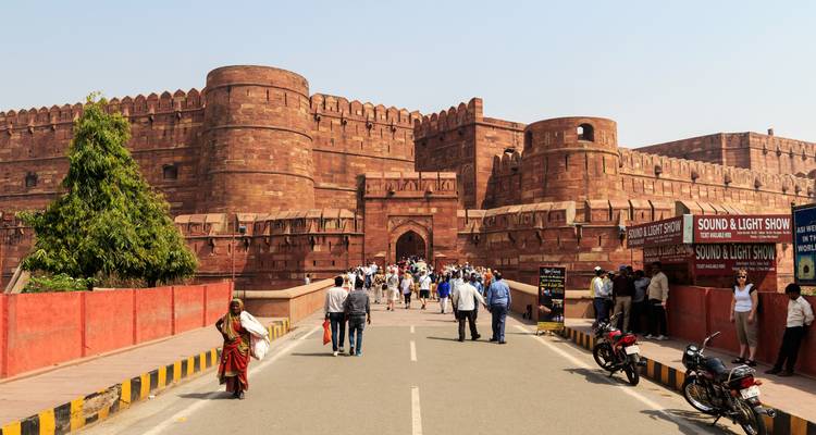 Historische Festung mit roten Sandsteinmauern und Touristen, die hindurchgehen.