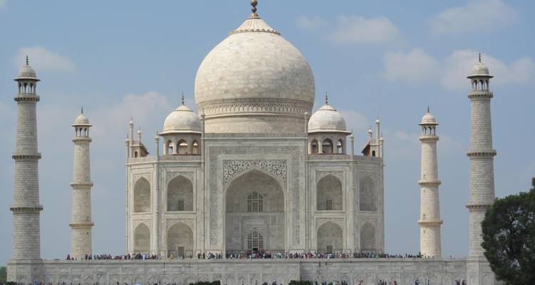 Das Taj Mahal mit blauem Himmel und Touristen im Vordergrund.