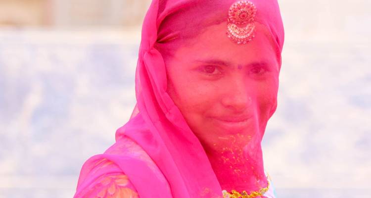 Portrait of a woman in traditional attire with a pink veil and jewelry.
