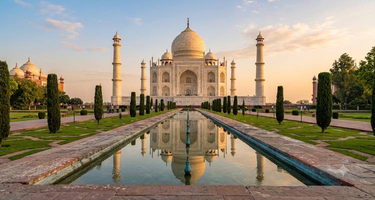 Sunrise glow on the Taj Mahal mirrored in its reflecting pool.
