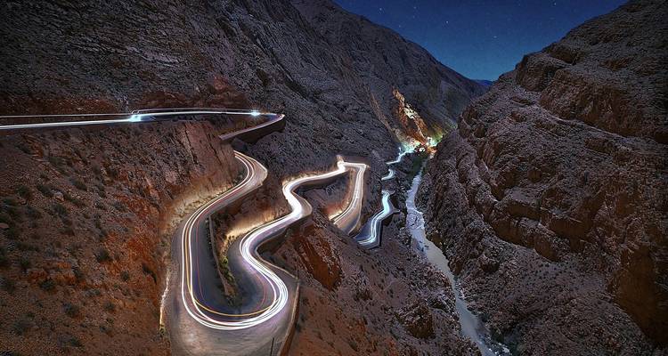 Kronkelende bergweg met lichtsporen in de nacht.