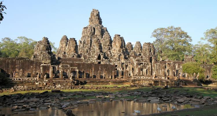 Oude stenen tempel met een reflectie in het water ervoor.