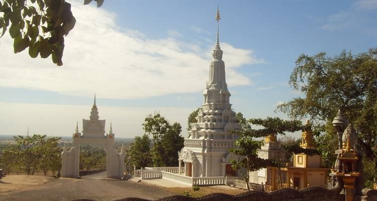 White pagoda and entrance arch amidst a scenic landscape under a clear sky.