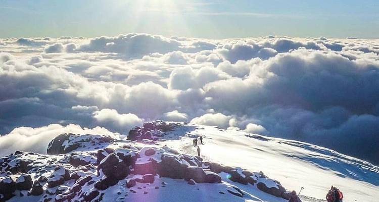 Wandelaars hoog boven de wolken in besneeuwd landschap.
