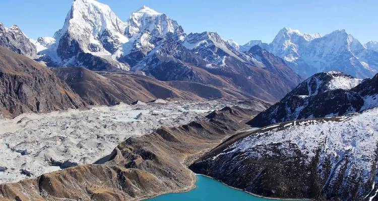 Lago Gokyo de color turquesa rodeado de morrenas y las dramáticas cumbres nevadas del Himalaya bajo cielos despejados.