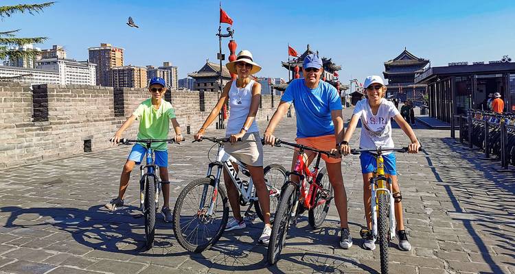 Familie fietst op stadsmuren in vrijetijdskleding.