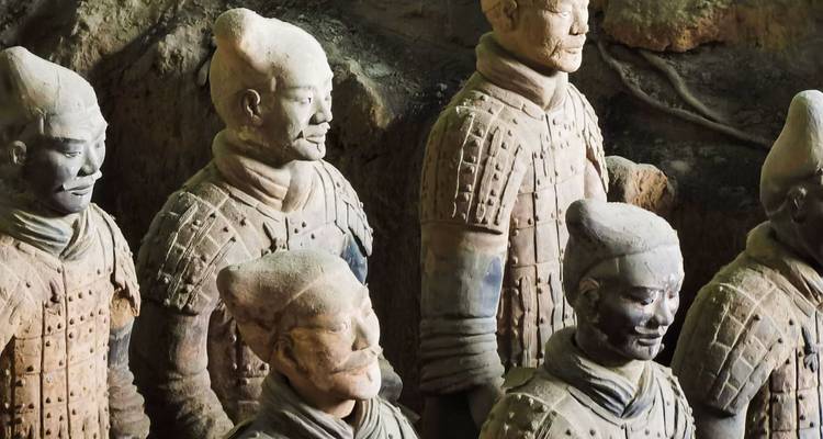 Primer plano de los Guerreros de Terracota de tamaño real de pie en su pozo de excavación con iluminación suave del museo.