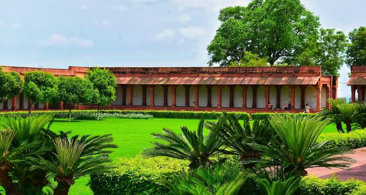 Zone de jardin luxuriant avec architecture historique en arrière-plan.