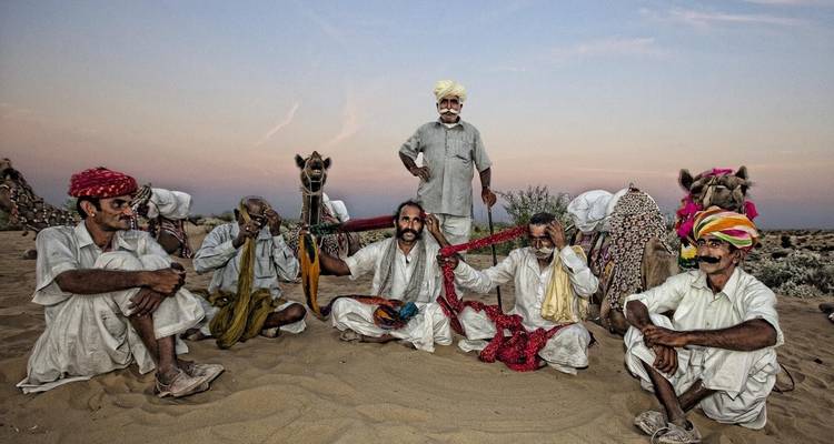 Group of men sitting in a desert setting.