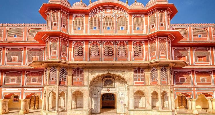 Een levendige rode paleisfaçade met gedetailleerde roostervensters.
