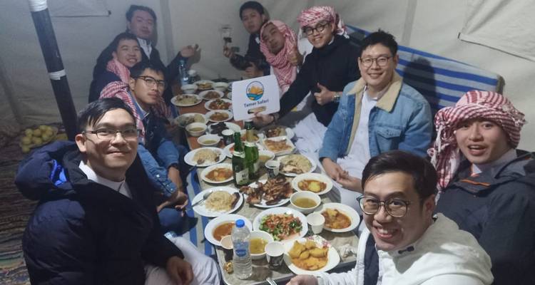 Gruppe von Menschen, die zusammen um einen großen Tisch speisen.