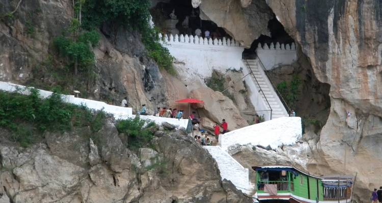 Des gens près d'une entrée de grotte creusée dans une falaise rocheuse.
