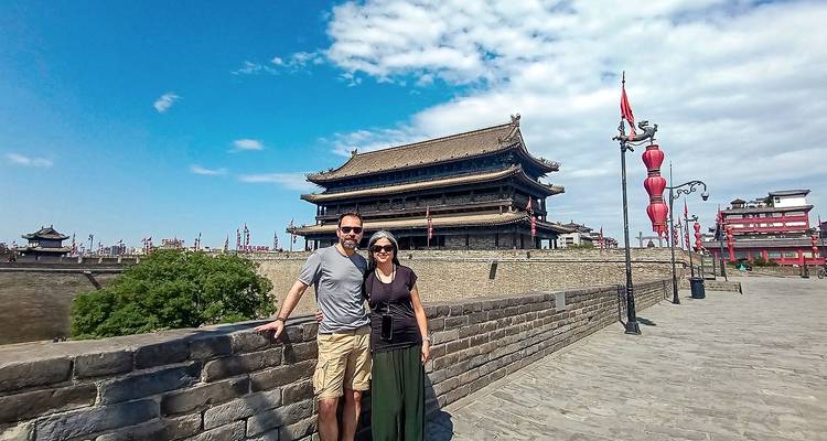 Couple debout sur un ancien mur de ville avec une porte chinoise traditionnelle.
