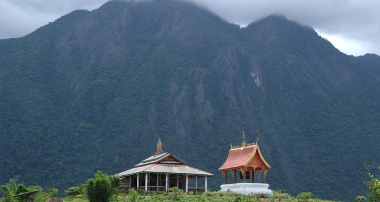 Petit temple avec un décor de montagne sous un ciel nuageux.
