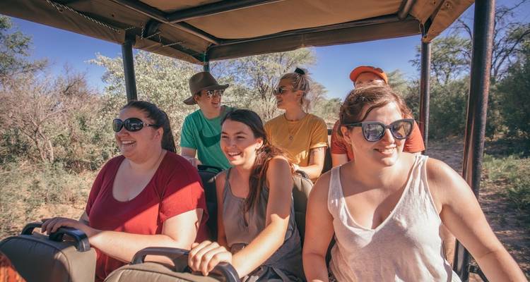 People on a safari vehicle in a dry landscape.