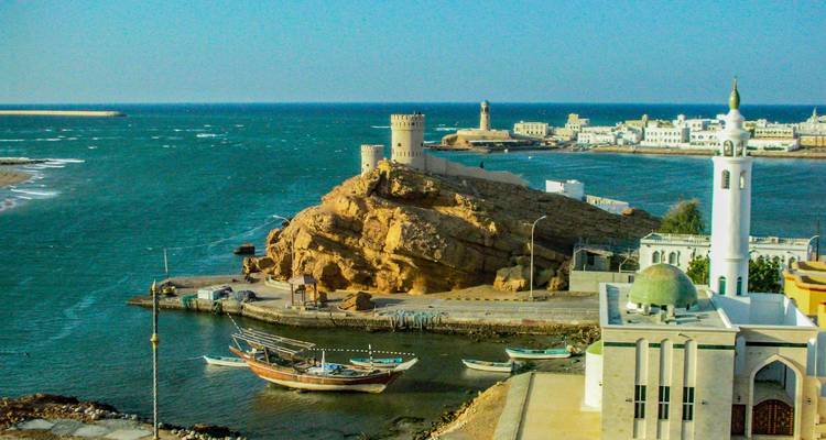 Kustplaats met traditionele boten en vestingwerken aan zee.