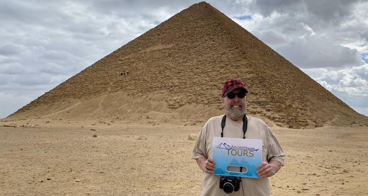 Tourist holding a sign with a pyramid behind.