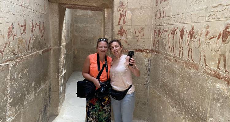 Two tourists with cameras standing in an ancient decorated corridor.